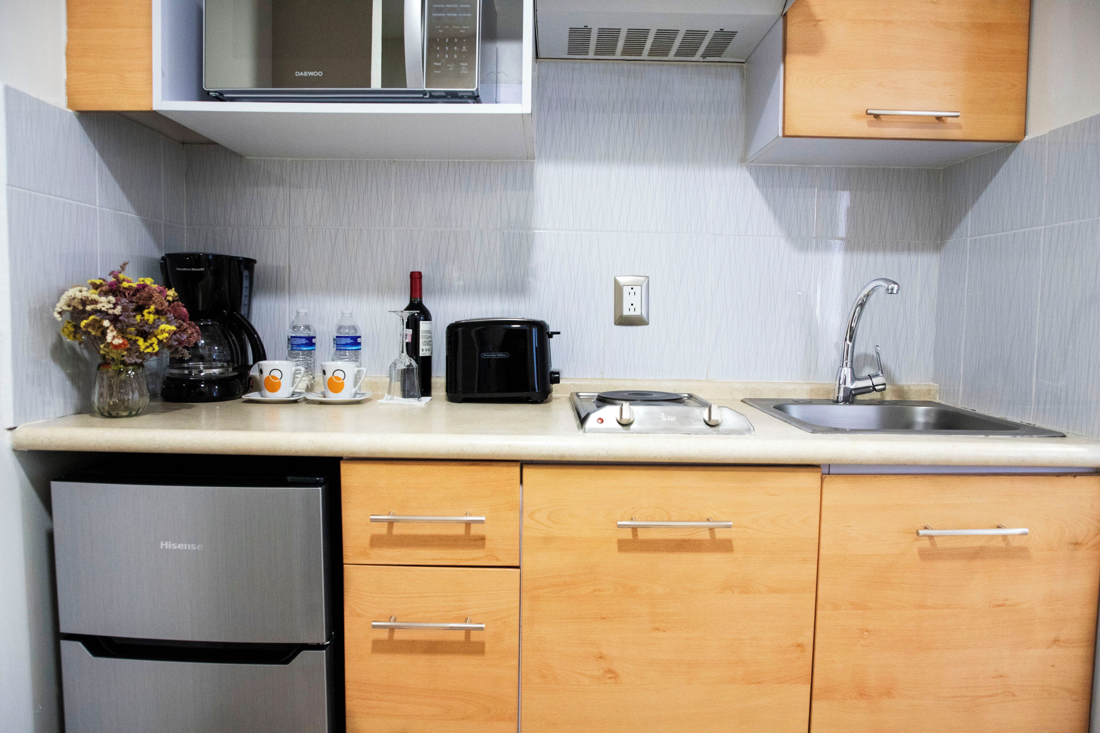 Una cocina compacta equipada con microondas, cafetera, tostadora y pileta.