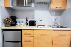 A compact kitchen with a microwave, coffee maker, toaster, and sink.
