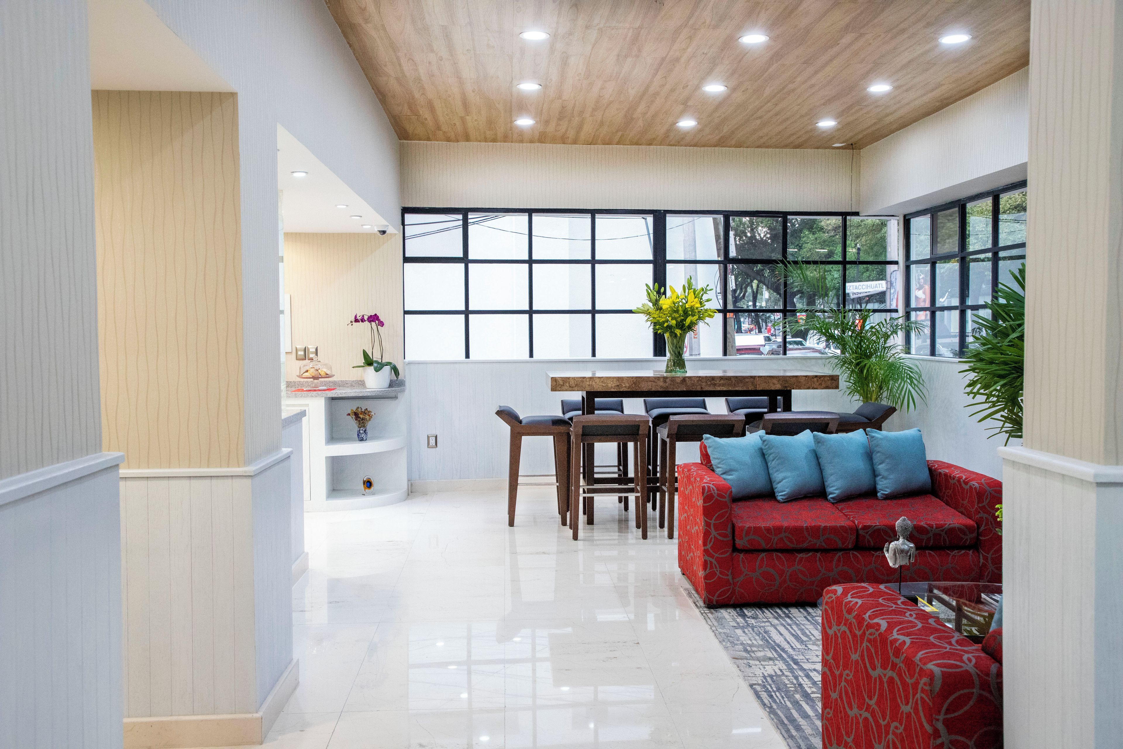 A spacious living area with a red sofa, a dining table with chairs, and a large window providing a view of the outside.