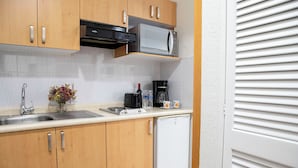 Una cocina compacta con microondas, cafetera y refrigerador pequeño.