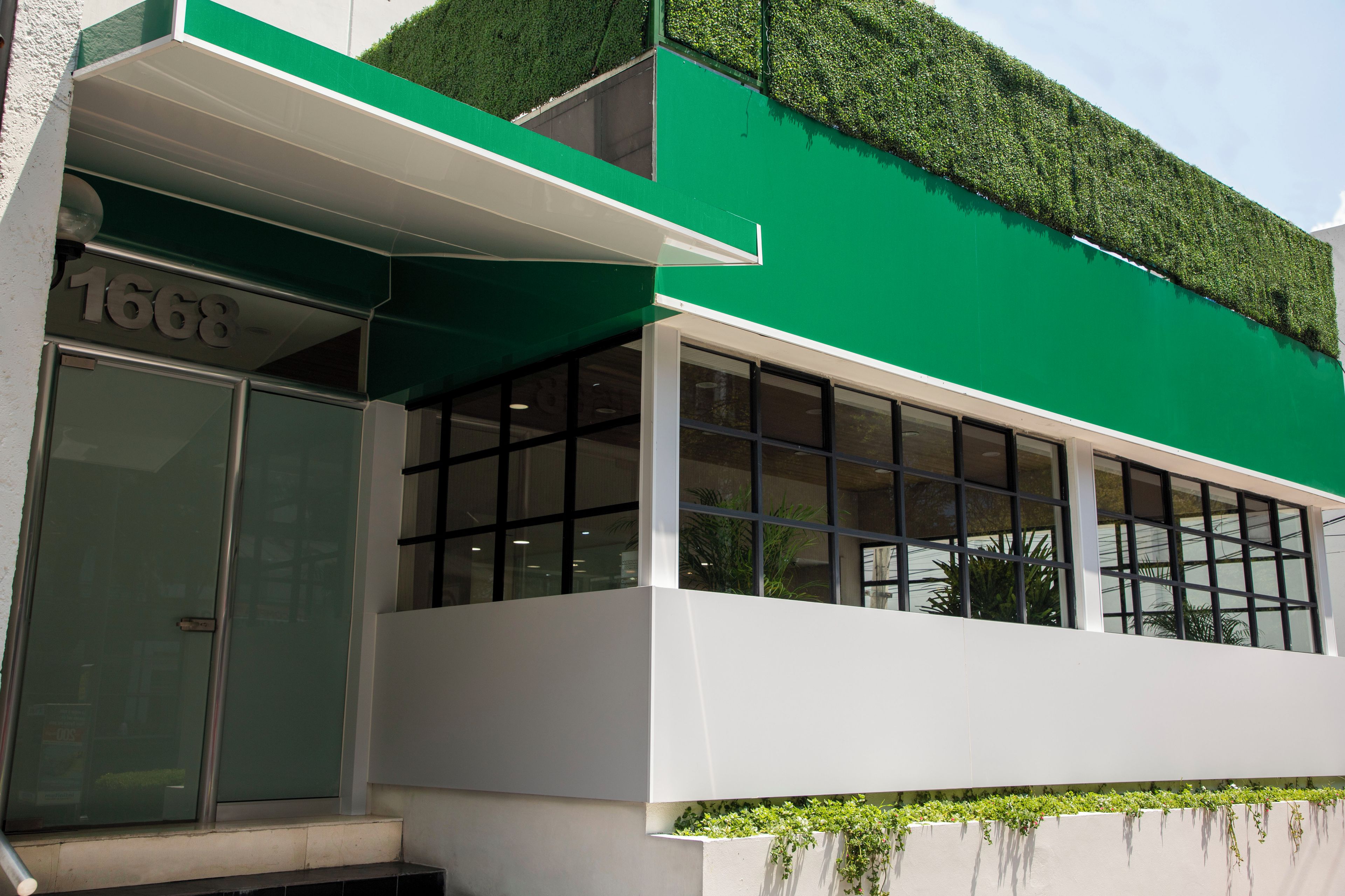 Un edificio con fachada verde, ventanas grandes y un número de matrícula visible.