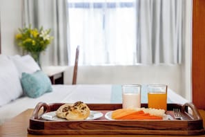 A breakfast tray with pastries, fruit, and two glasses of milk and juice on a wooden tray in a hotel room. - Suites Coben (Tlalnepantla de Baz)