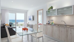 A modern kitchen with a glass dining table, white chairs, and a view of the sea. - Casa Mercedes, Apt 1 - Sea View and Terrace, Puerto del Carmen - Lanzarote (Puerto del Carmen)