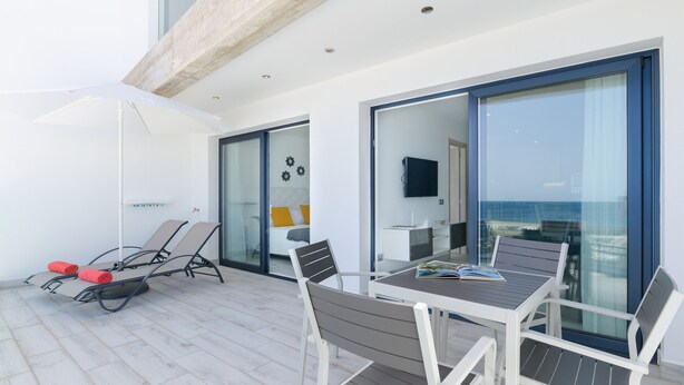 A balcony with a table and chairs, a white umbrella, and a view of the sea. - Casa Mercedes, Apt 1 - Sea View and Terrace, Puerto del Carmen - Lanzarote (Puerto del Carmen)