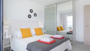 A modern bedroom with a large bed, a mirror, and a nightstand. - Casa Mercedes, Apt 1 - Sea View and Terrace, Puerto del Carmen - Lanzarote (Puerto del Carmen)