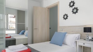 Una habitación de hotel moderna con cama, mesita de noche, lámpara y armario.