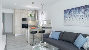 Una cocina moderna con una isla central, taburetes de bar y una mesa de centro de vidrio.