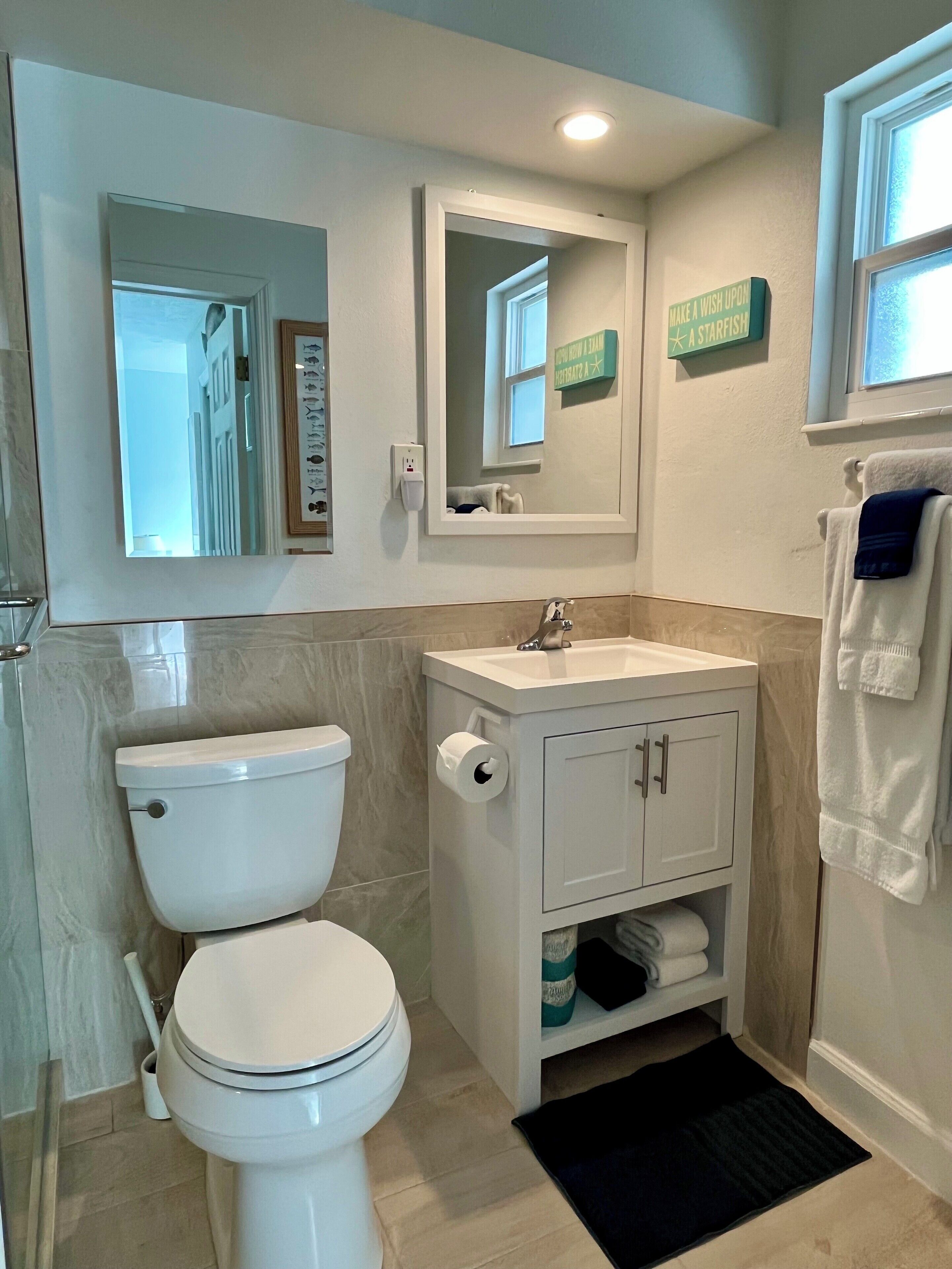 A bathroom with a toilet, sink, mirror, and towel rack.
