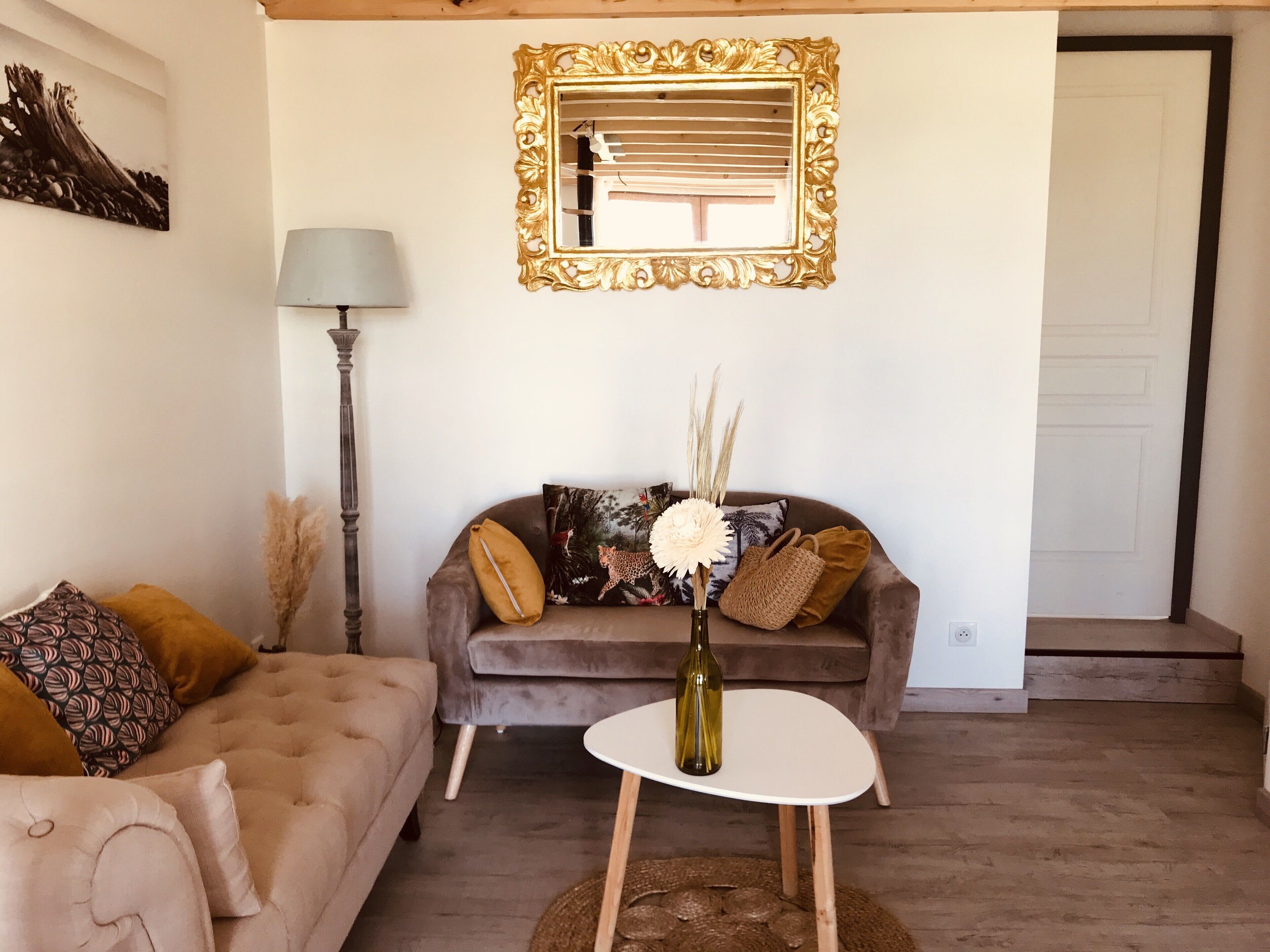 Un salon avec un canap é, une petite table, une lampe et un miroir.