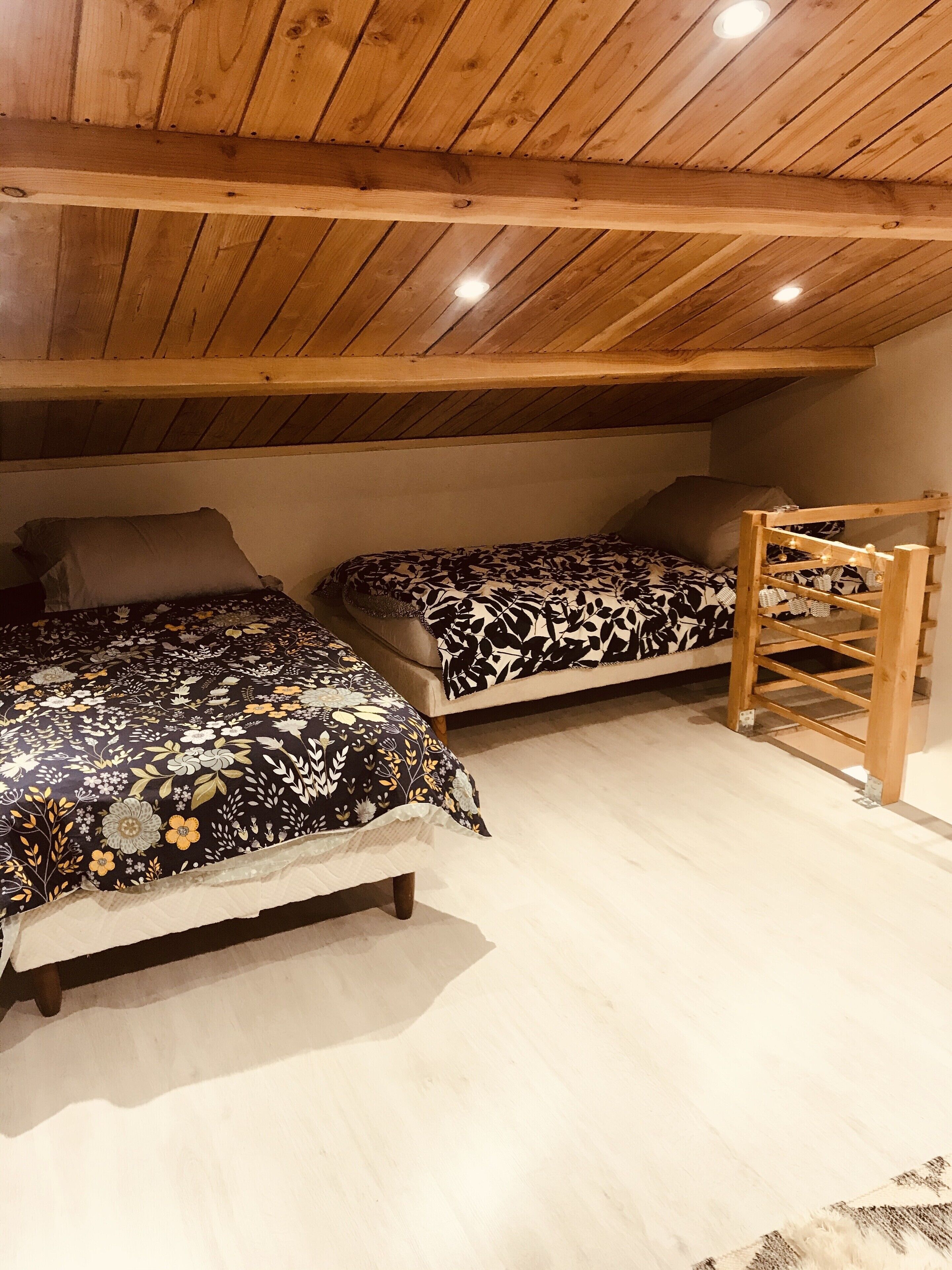 Ein gemütliches Schlafzimmer im Dachgeschoss mit zwei Betten, Holzbalken und einer geneigten Decke.