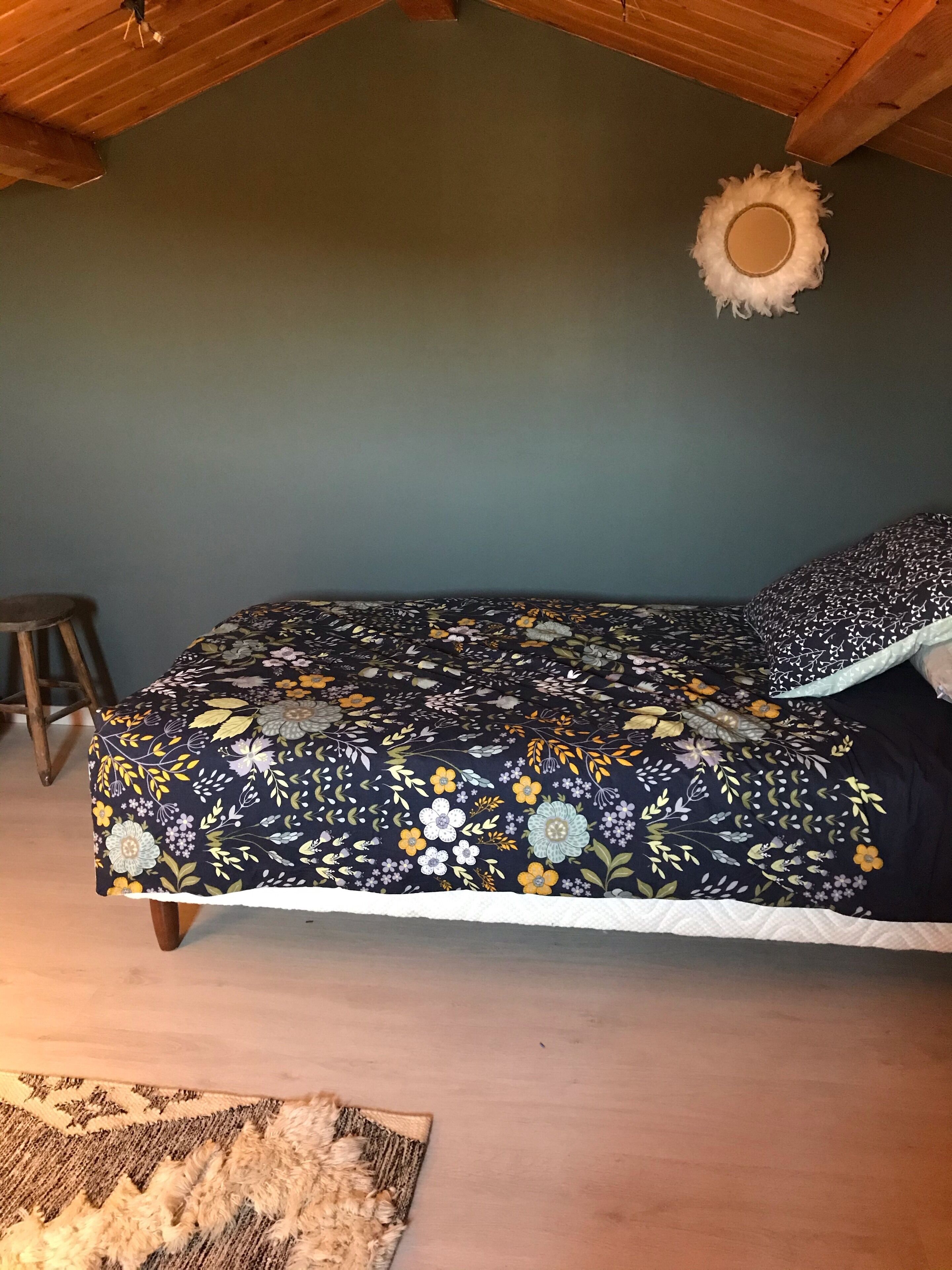 Une chambre à coucher avec un lit, un petit tabouret et un tapis.