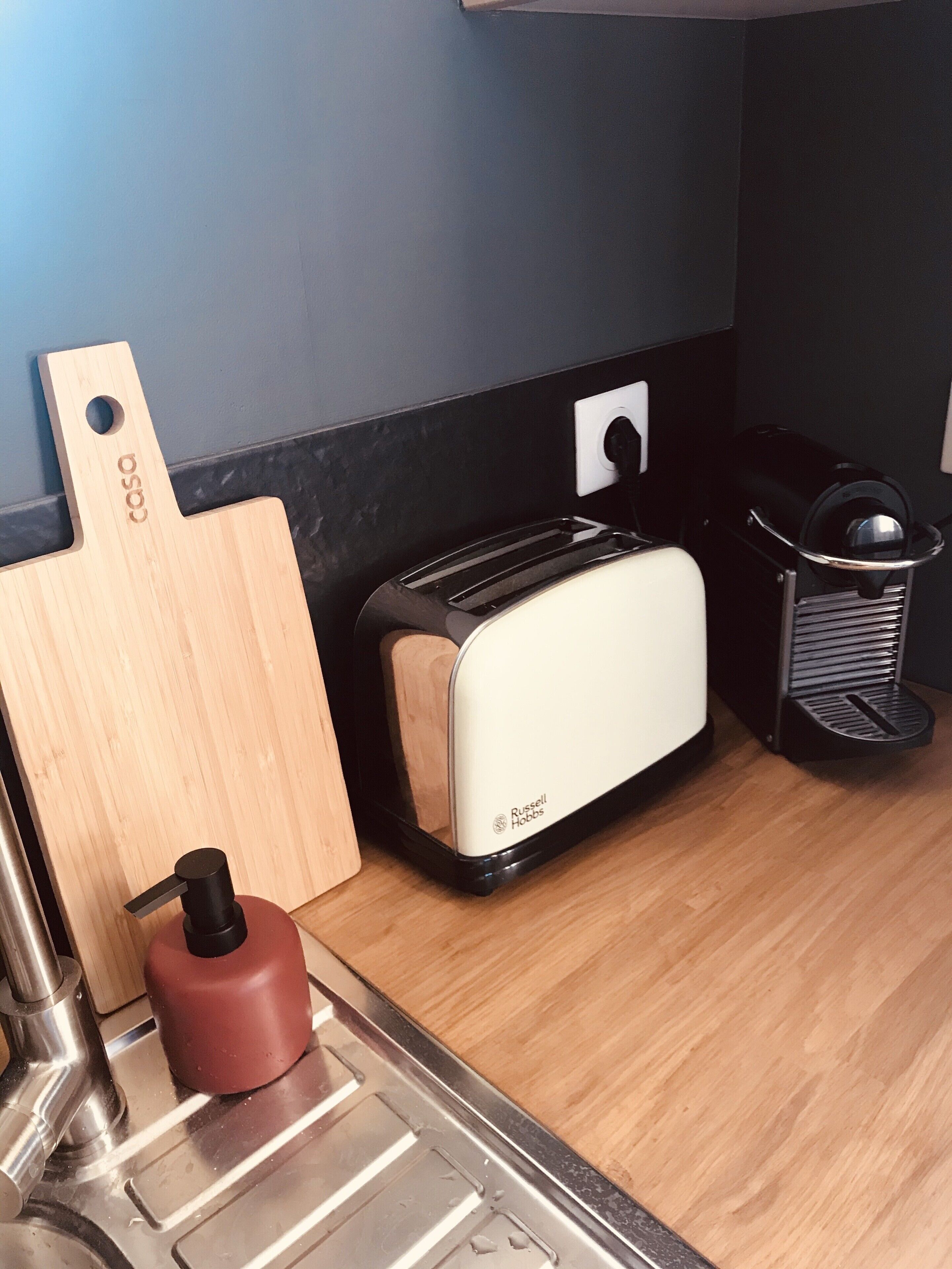A kitchen with a toaster, a knife block, and a trash can.