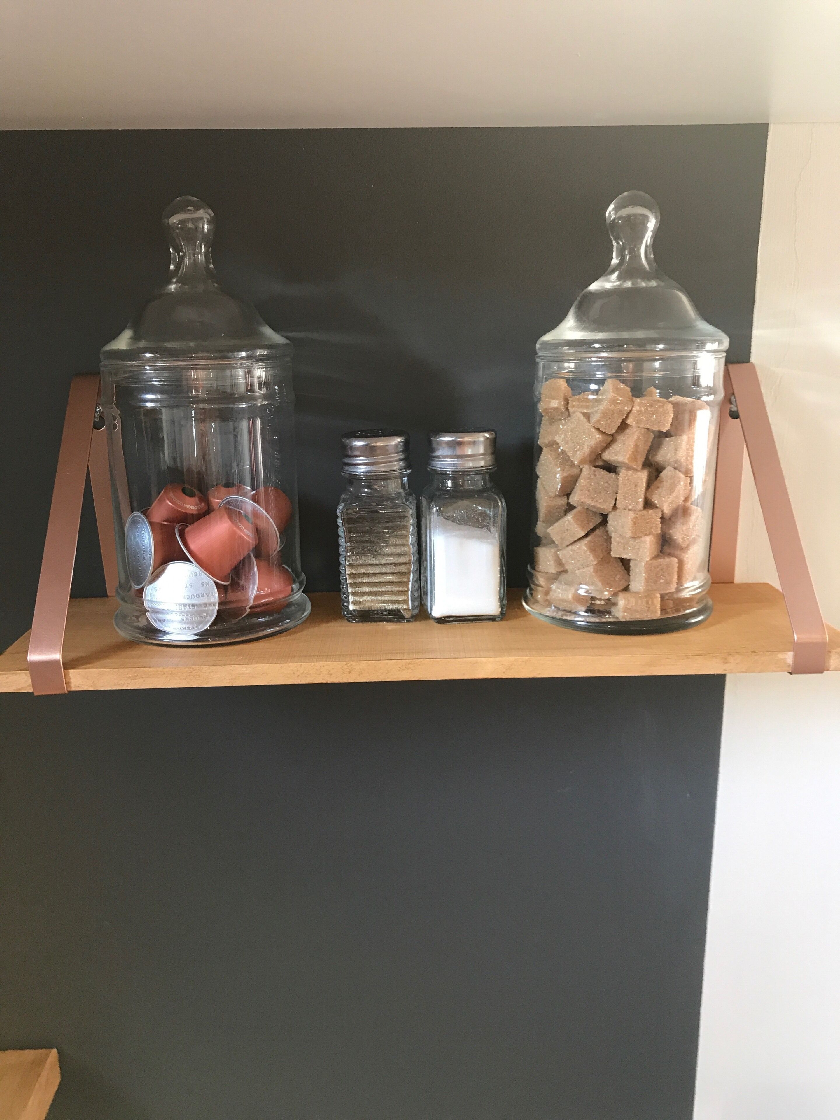 Une étagère sur laquelle reposent trois récipients en verre contenant divers objets.