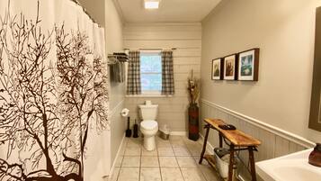 Een bad/douchecombinatie, een haardroger, handdoeken, zeep