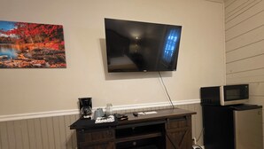 A living room with a mounted TV, a coffee maker, a microwave, and a refrigerator. - Standard Guest Room (Main) - Barefoot Hills - North Georgia Mountains (Dahlonega)