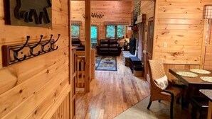 L’intérieur d’une cabane en bois comprend un coin repas, un salon et un couloir qui mène à une véranda.