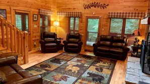 L’intérieur chaleureux d’un chalet avec des murs en bois, une cheminée, des canapés en cuir et un tapis à motifs.