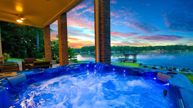 Un jacuzzi con vista a un lago y al atardecer.