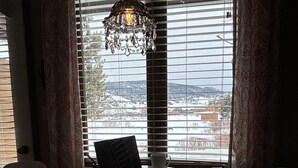Ein Zimmer mit einem runden Tisch, zwei weißen Stühlen, einem Laptop und einer Chandelüster.