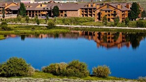 Eine Lodge mit mehreren Gebäuden, einem stillen See und umgebender Vegetation.