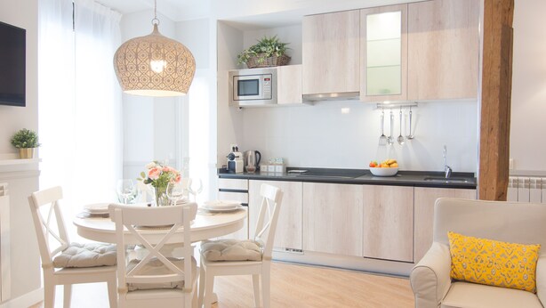A modern kitchen with a dining area, featuring a round table, white chairs, and a hanging light fixture. - Stylish Apt PZA MAYOR / La Latina 2BD * 2BT *, 6p max (Madrid)