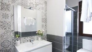 A modern bathroom with a large mirror, white sink, and a glass shower enclosure. - Stylish Apt PZA MAYOR / La Latina 2BD * 2BT *, 6p max (Madrid)