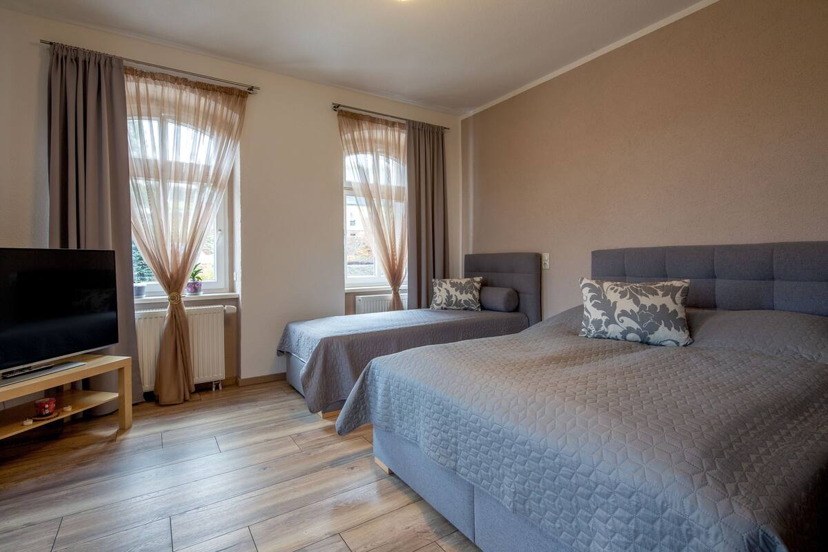 Quarto de hotel com duas camas, televisão e janela com cortinas.