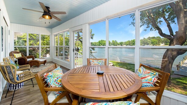 A sunroom with a wooden table and chairs, large windows, and a ceiling fan. - Summer Status (Mooresville)