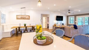 A spacious living area with a dining table, chairs, a sofa, and a TV. - Summer Status (Mooresville)