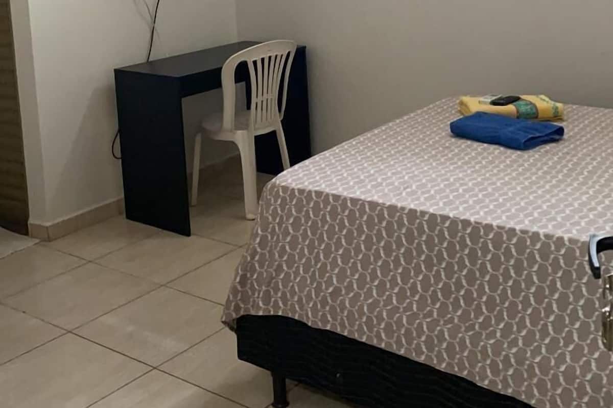 Ein Schlafzimmer mit Bett, Schreibtisch, Stuhl und Klimaanlage.