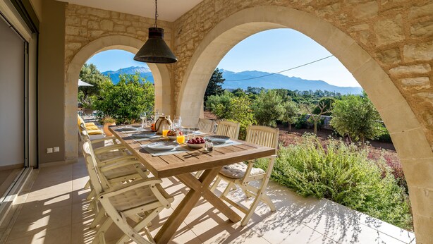 A dining area with a stone archway, a wooden table, and chairs.