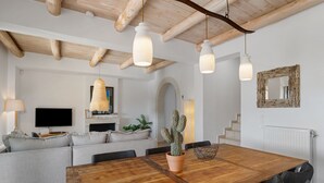 A modern living room with a wooden dining table, grey sofa, and a cactus plant.
