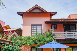 A pink building with a tiled roof, a window, and a balcony. - Residencial Bahia do Sonho (Bombinhas)