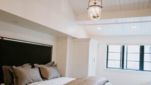 Et soveværelse med seng, skab, et vindue og en loftlampe.