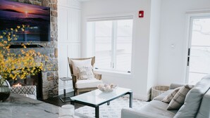 A living room with a stone fireplace, a flat-screen TV, a comfortable sofa, and a coffee table. - Ocean View Penthouse (Carmel-by-the-Sea)