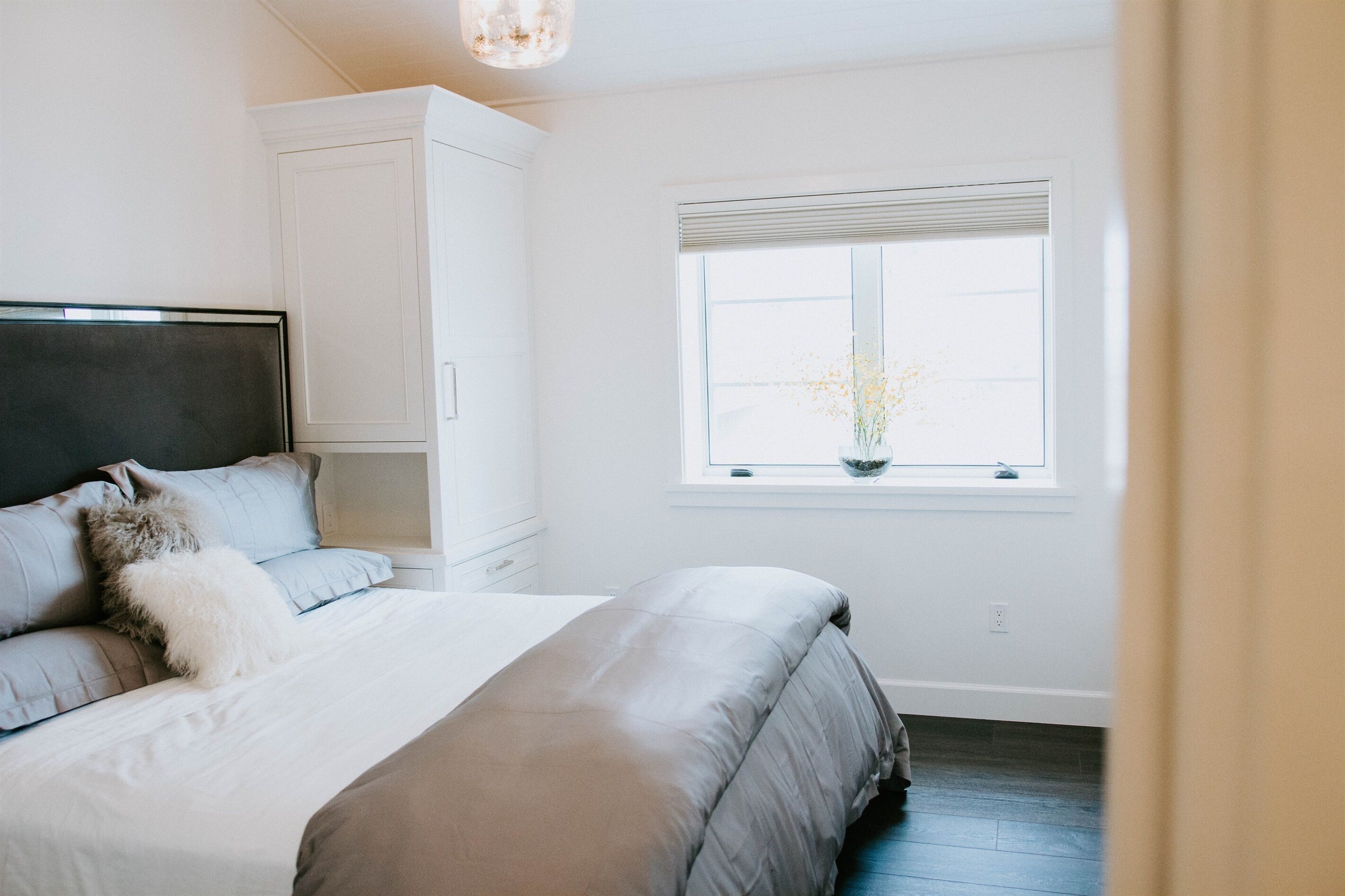 Une chambre à coucher avec un lit, une fenêtre donnant sur un beau paysage et une armoire blanche.