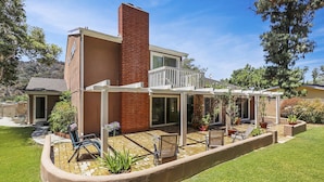 A modern house with a patio, a brick chimney, and a covered outdoor seating area.