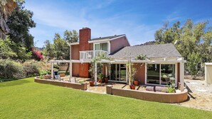 A modern house with a covered patio, a brick chimney, and a well-maintained lawn.