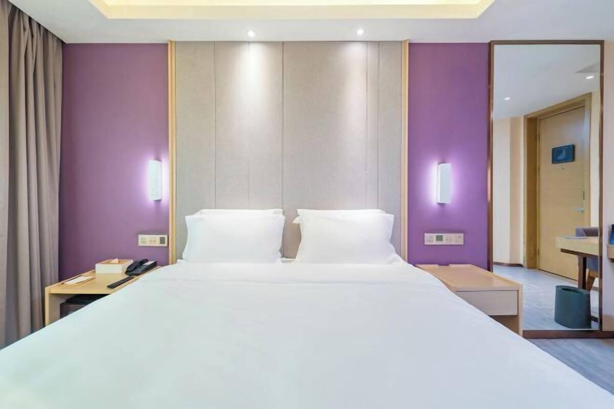 A hotel room with a large bed, two bedside tables, a desk, and a mirror.