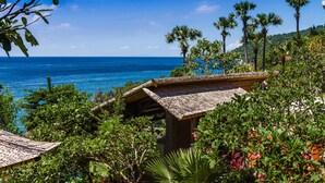 A tropical resort with a view of the ocean, surrounded by lush greenery and palm trees. - Aquamarine Beach Villas (Karangasem)