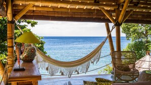 A hammock chair and a wicker chair under a bamboo structure with a view of the ocean. - Aquamarine Beach Villas (Karangasem)