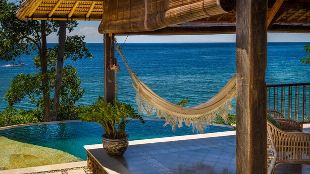 A hammock under a wooden pergola overlooking a pool and ocean. - Aquamarine Beach Villas (Karangasem)