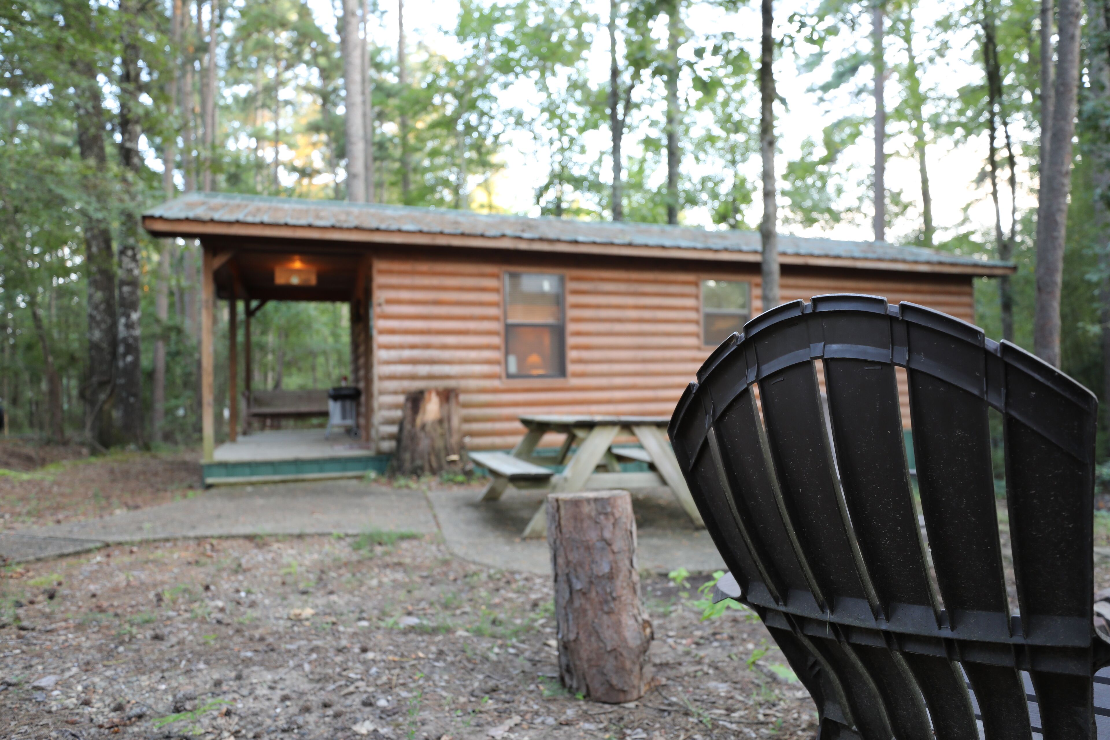 A rustic cabin with a picnic table and a wooden chair in the foreground.
