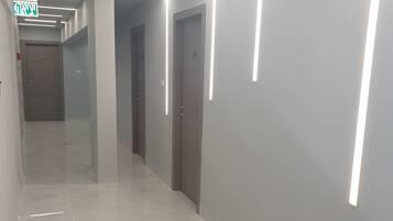 Een gang met een glanzende vloer, ingebouwde verlichting en deuren.