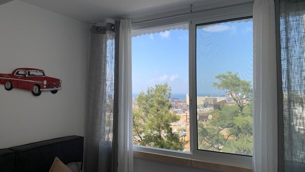 Ein Zimmer mit einem Bett, einem Fenster mit Vorhängen und einer roten Auto-Dekoration an der Wand.