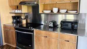 A modern kitchen with wooden cabinets, stainless steel appliances, and a coffee maker. - Bishop Arts Hotel Penthouse Suite 7 (Dallas)