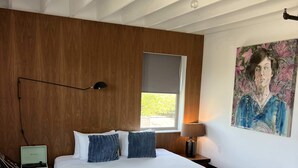 A modern bedroom with a large bed, wooden flooring, a painting on the wall, and a window with a view. - Bishop Arts Hotel Penthouse Suite 7 (Dallas)
