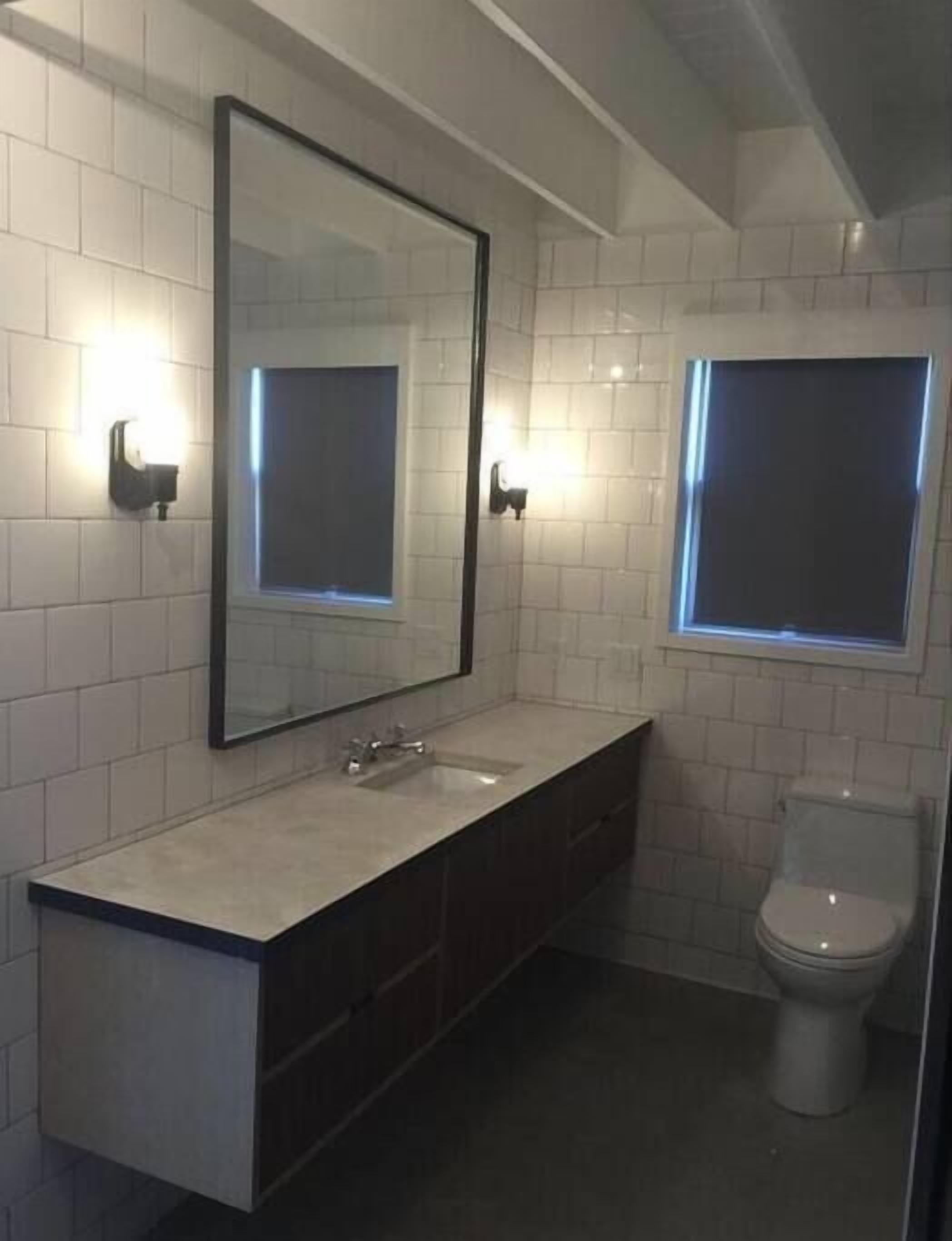 Een moderne badkamer met een grote spiegel, een wastafel en een toilet.