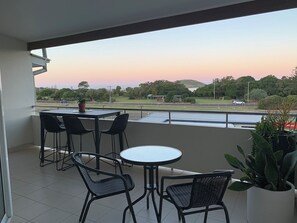 Enjoy the unobstructed view of the surrounding landscape from this balcony, featuring a seating area with two tables and four chairs.