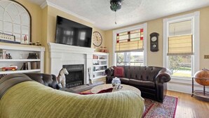 Una sala de estar con chimenea, sofá de cuero y televisión montada en la pared.